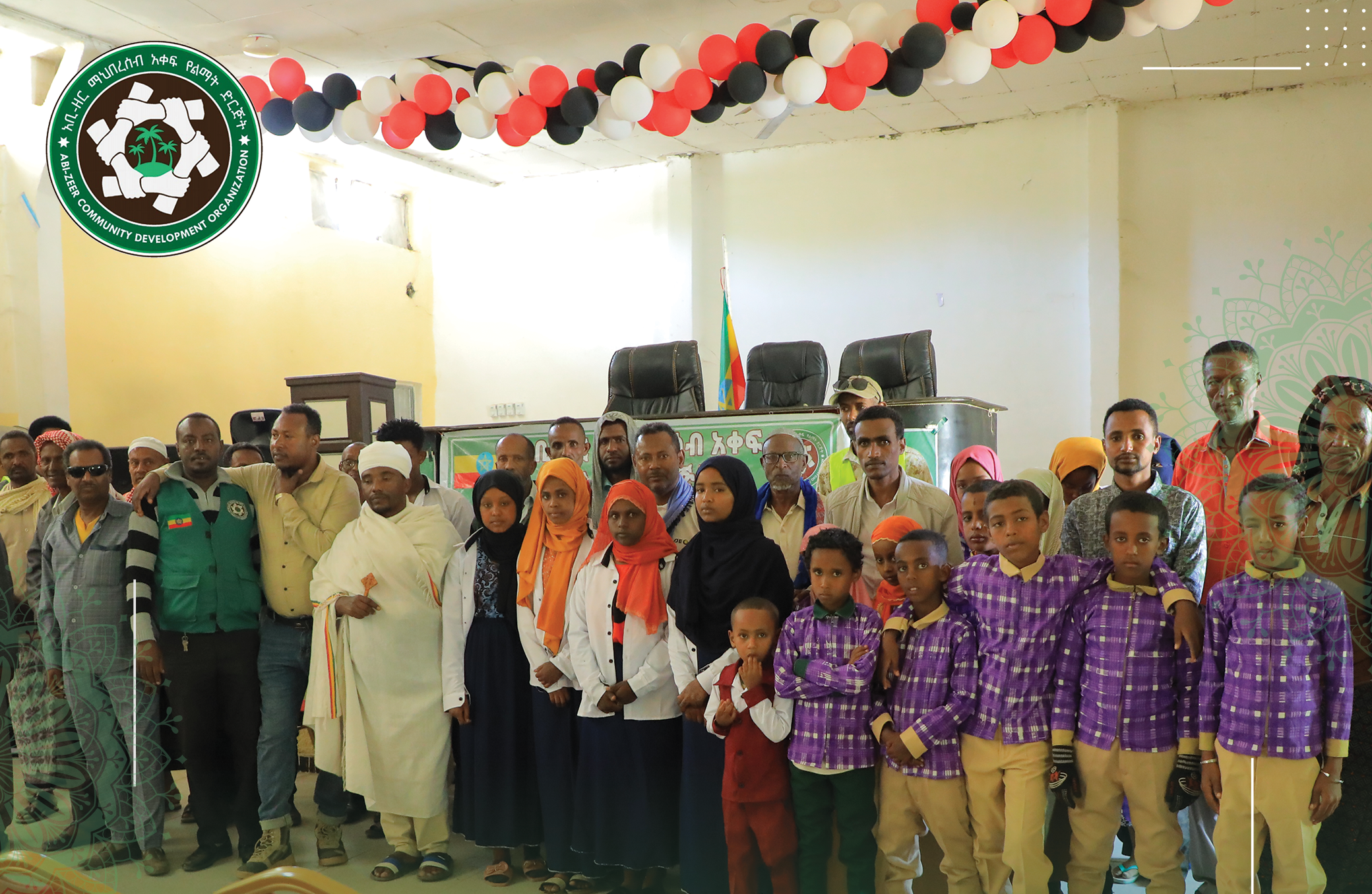 A group photo of community leaders, coordinators, and young students wearing matching purple patterned school uniforms, taken during a school uniform distribution event organized by the Abizeer Community Development Organization